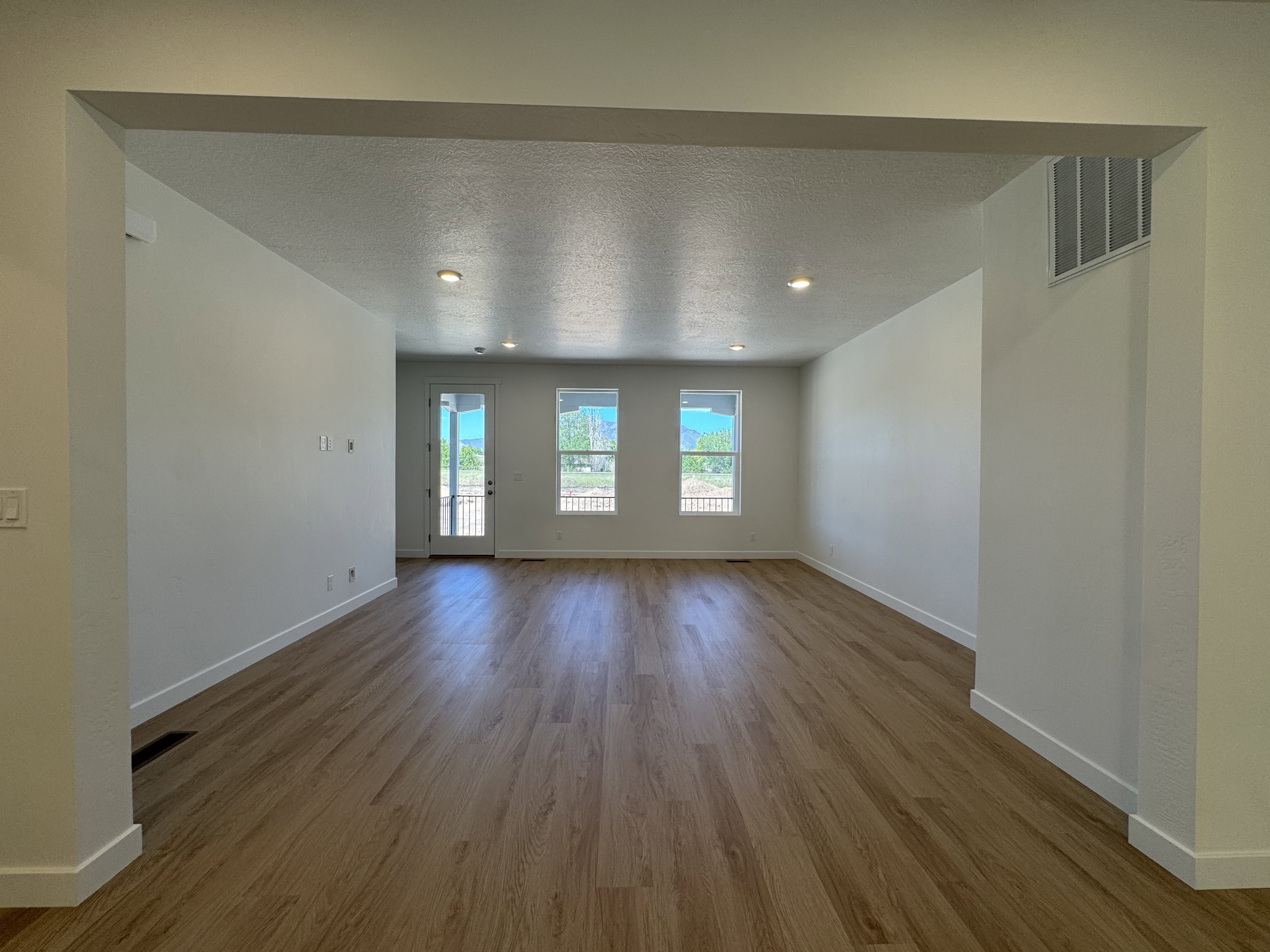Spacious interior with wood-finish flooring, recessed lighting, and white baseboards