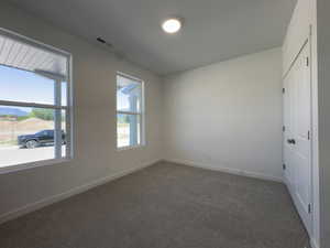 Carpeted room featuring two large windows, white walls, and a white paneled door