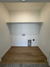 Dedicated laundry area featuring wood-finish flooring, a built-in shelf, and crisp white walls