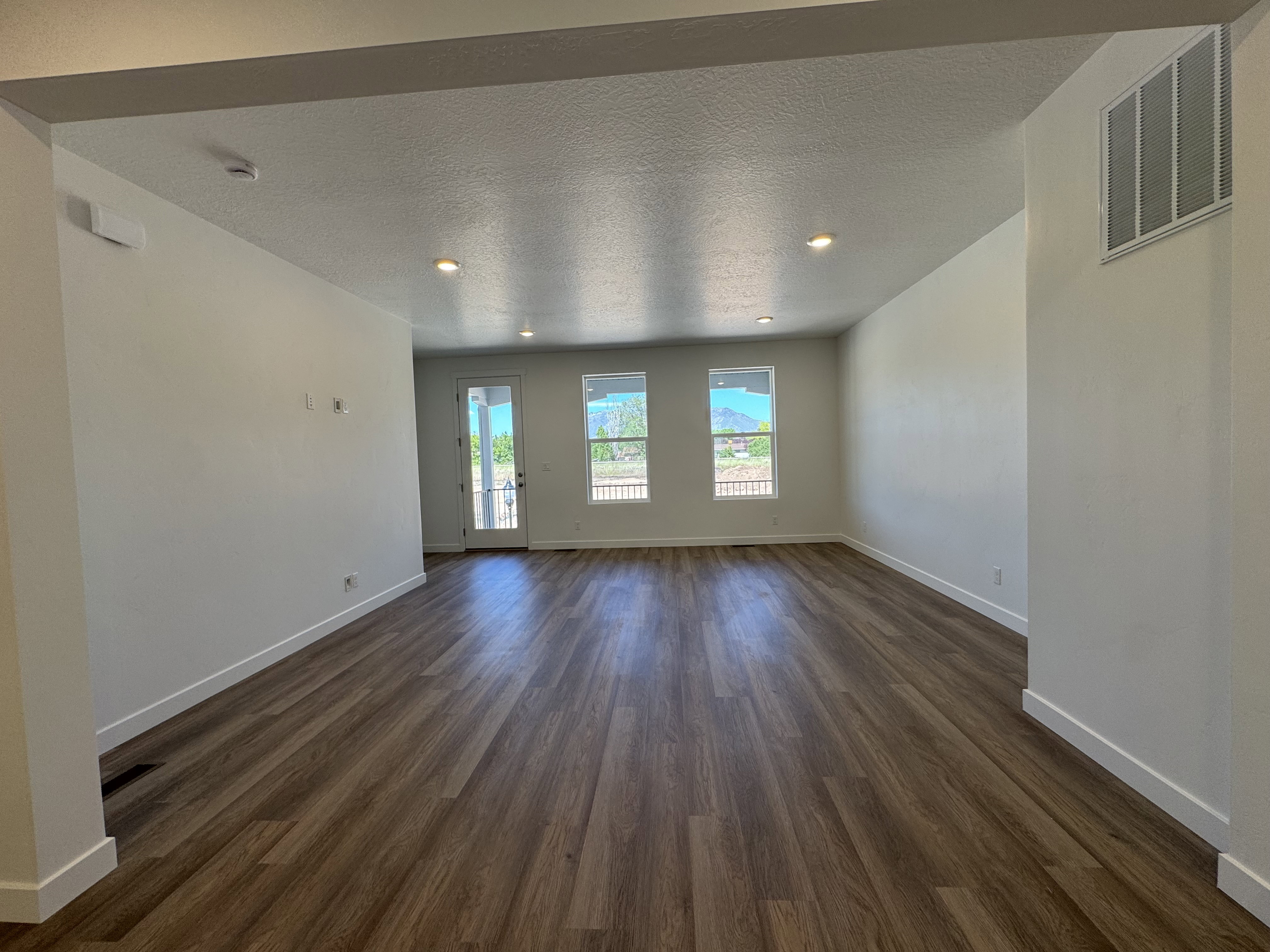 Spacious interior featuring wood-finish flooring, recessed lighting, and white baseboards