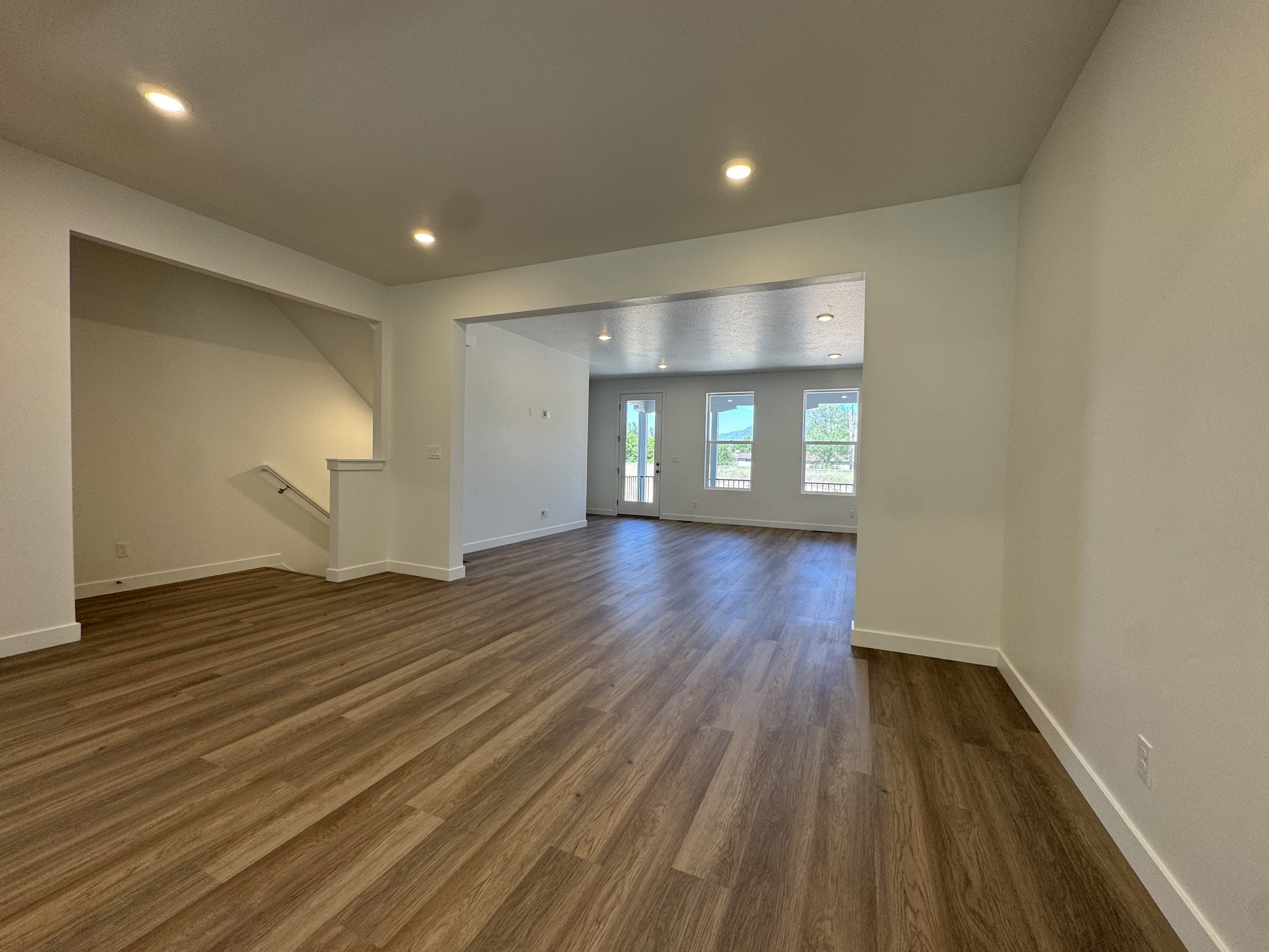 Spacious open-concept living area featuring wood-finish flooring, recessed lighting, and white baseboards