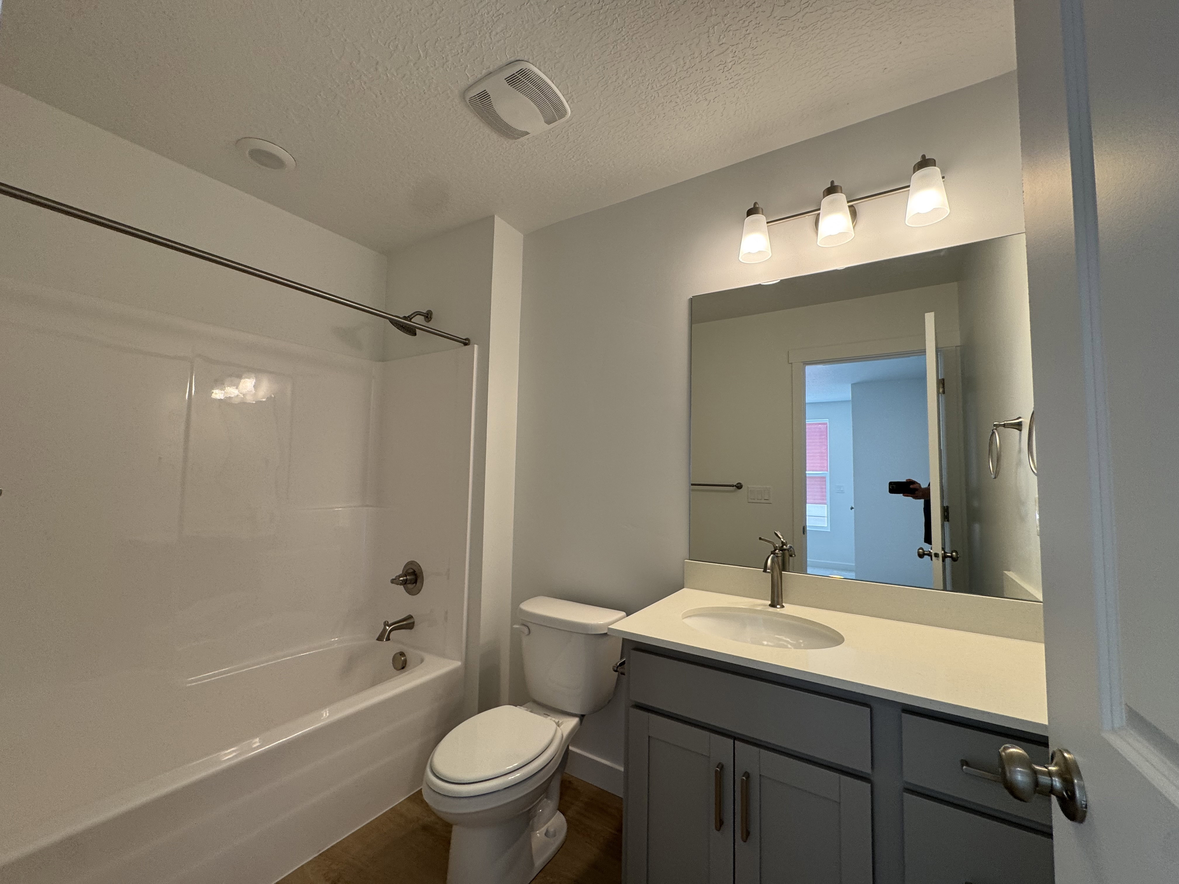 Full bathroom featuring a white tub/shower combination, brushed nickel fixtures, a gray vanity with a single sink, and a large wall-mounted mirror