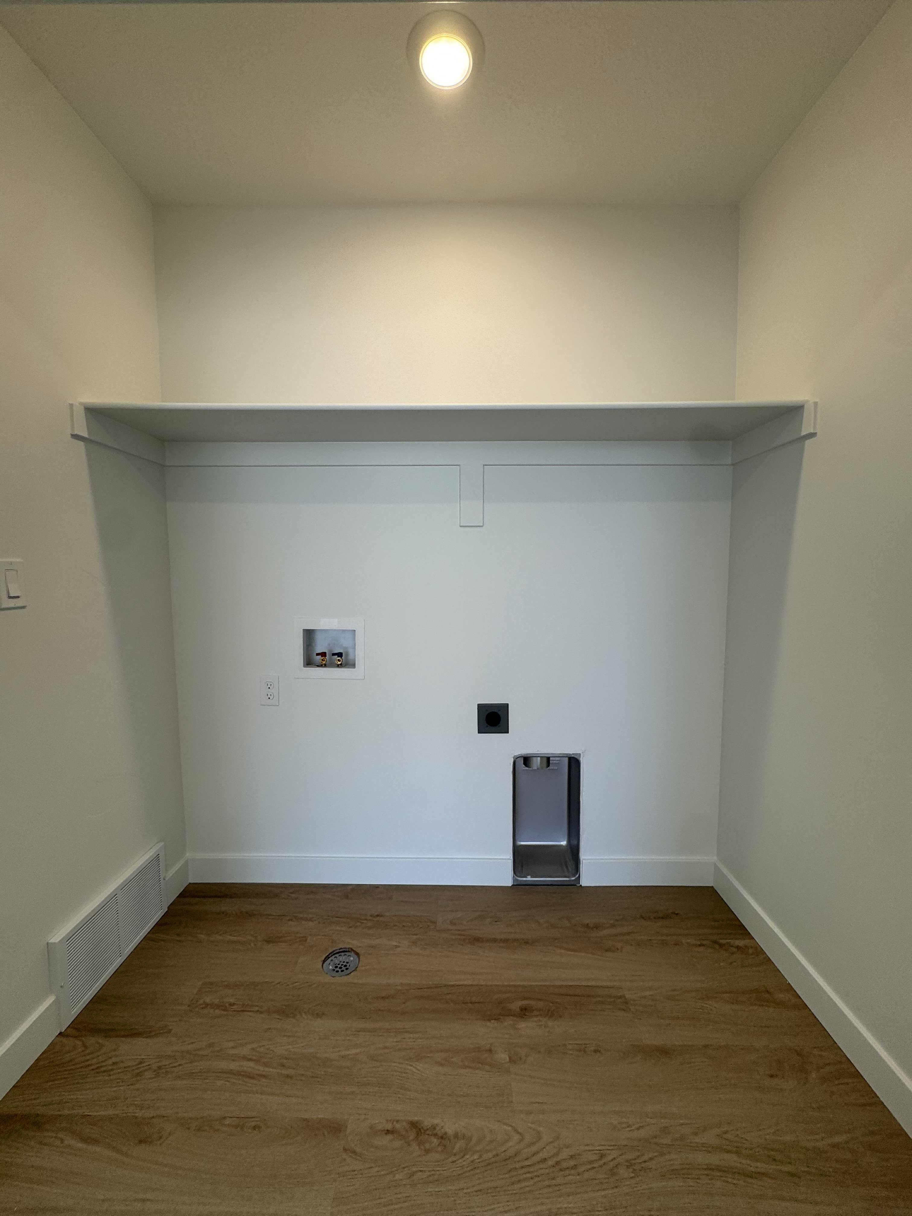 Dedicated laundry area featuring wood-finish flooring, white walls, and a recessed ceiling light