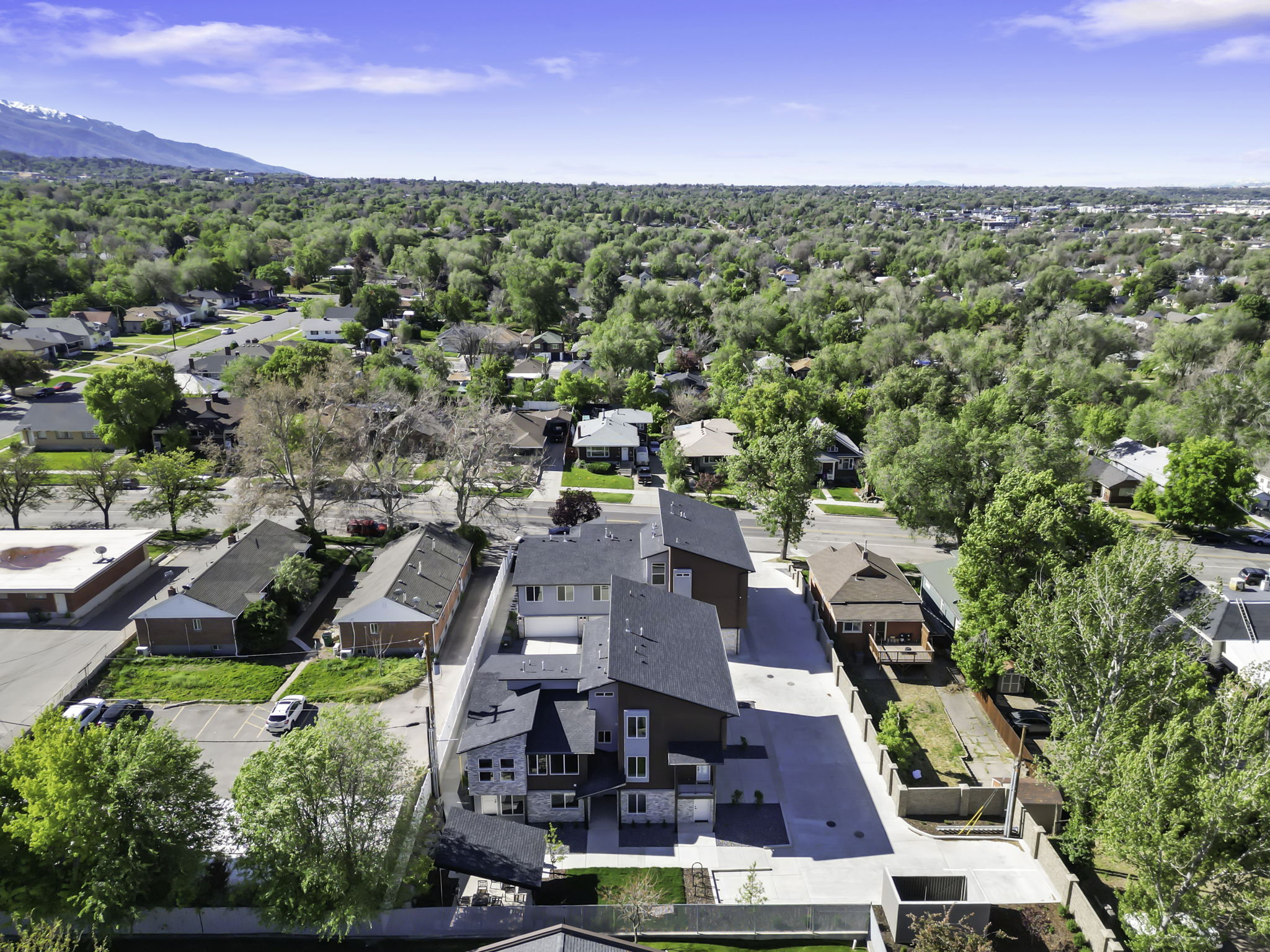 Modern multi-unit development featuring contemporary architecture, stone and wood-look siding, a flat roofline, and paved parking areas