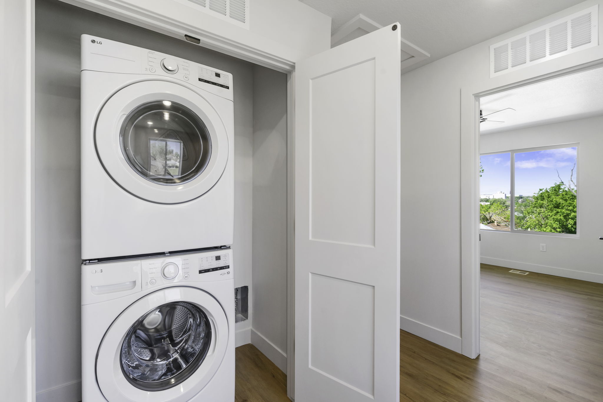 Dedicated laundry closet featuring a stacked white washer and dryer unit included