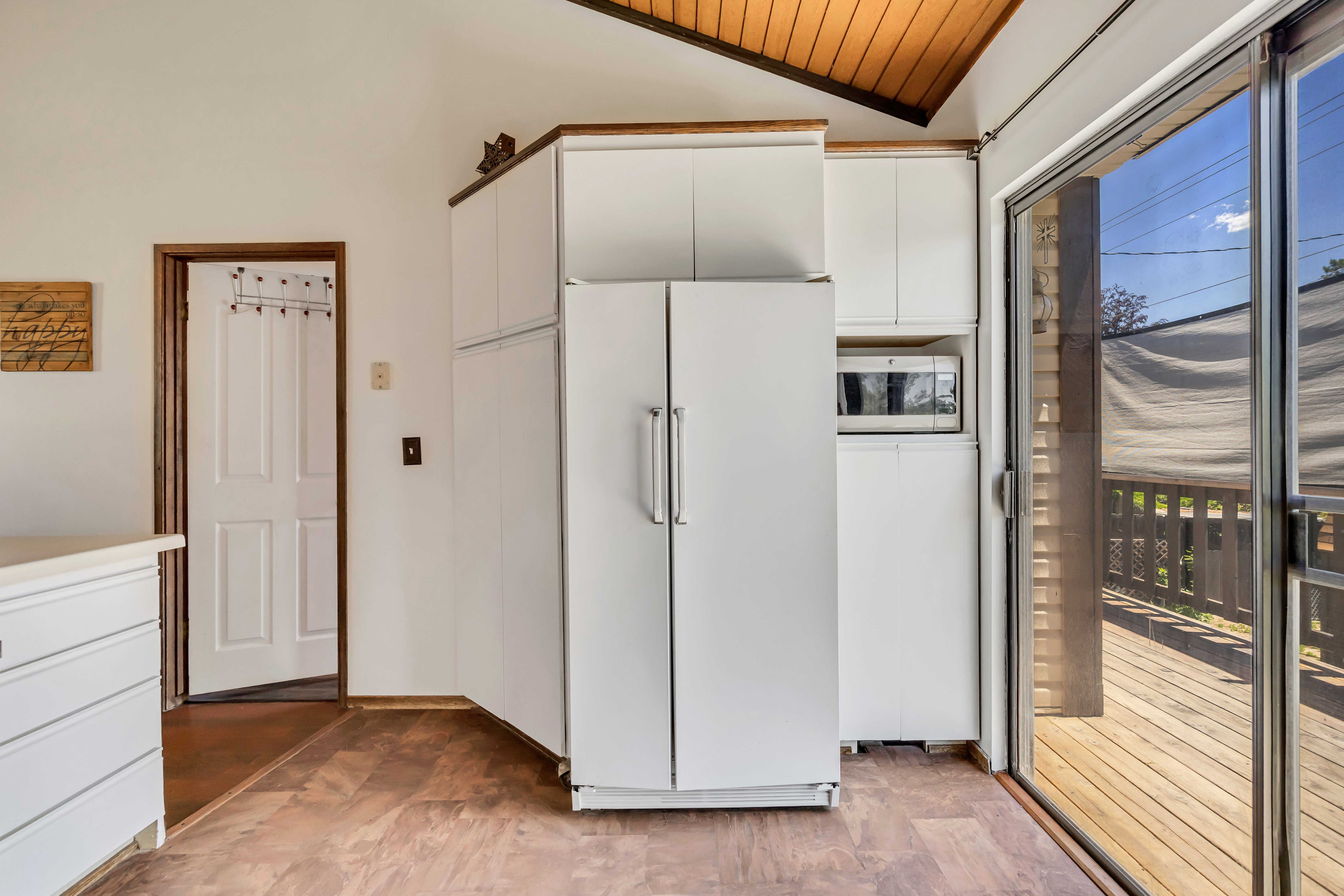 Kitchen area featuring wood-finish flooring, white cabinetry, and a built-in microwave oven