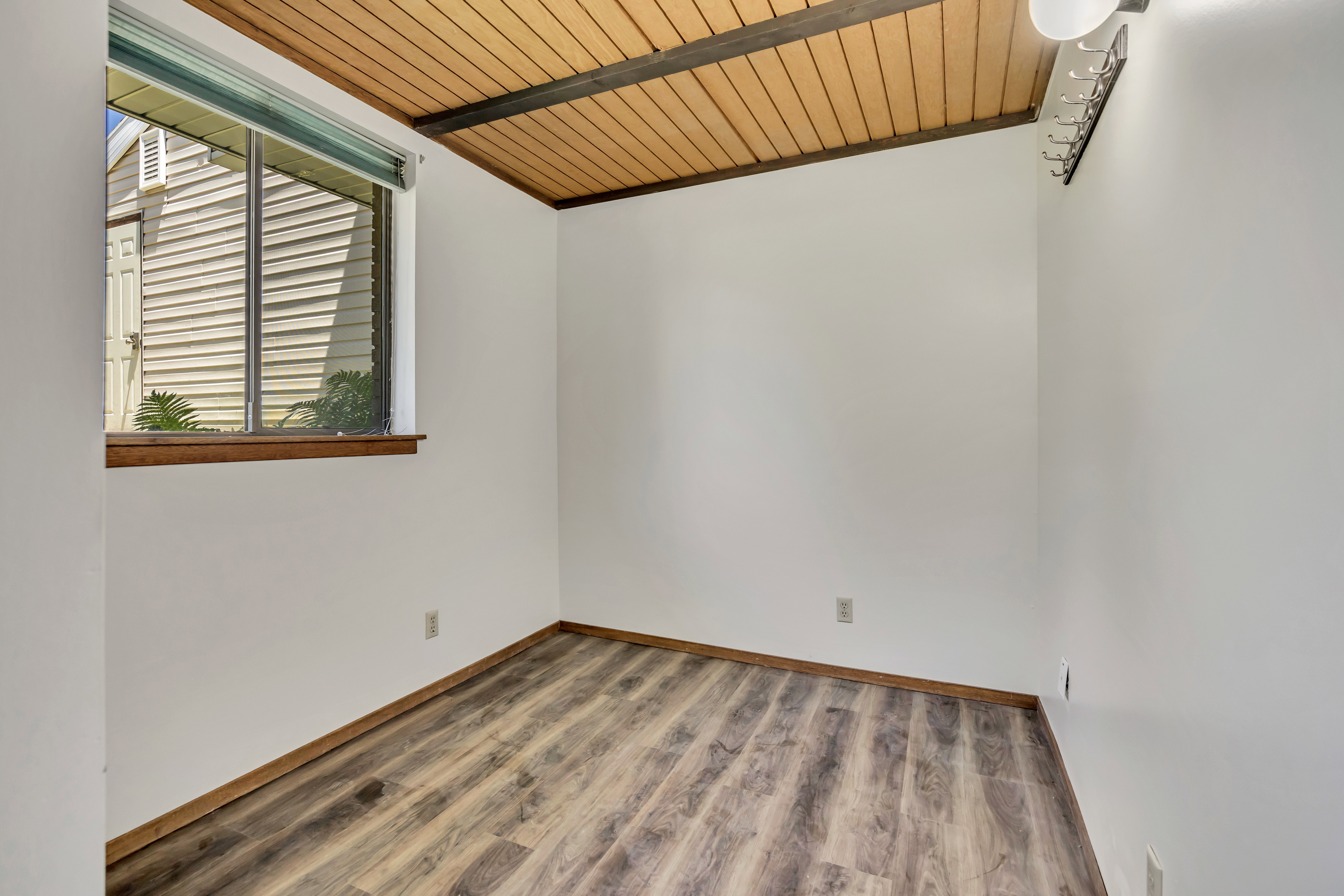 Room featuring wood-finish flooring, white walls, and a window with a wood sill