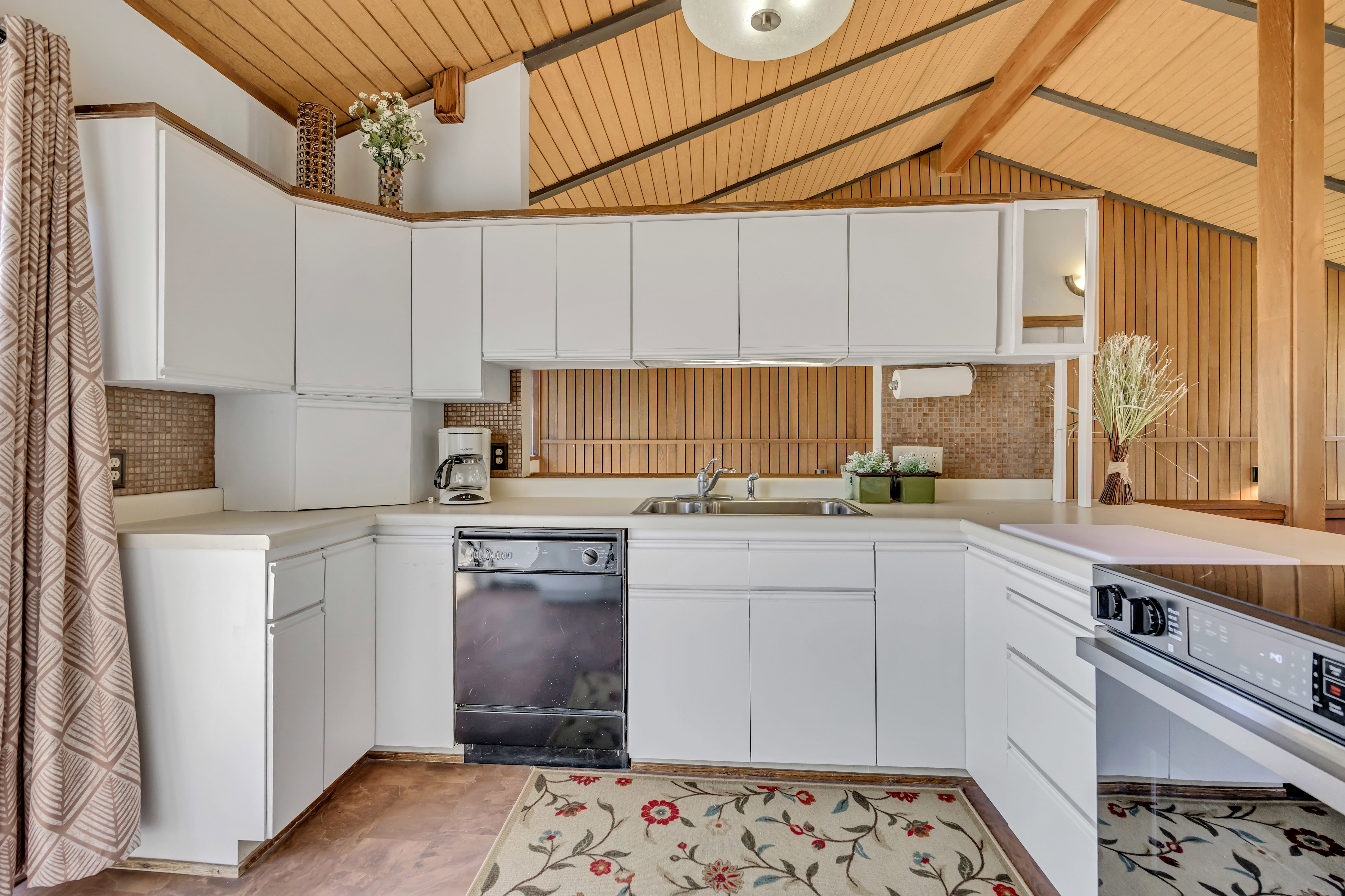 Kitchen featuring white cabinetry, solid surface countertops, mosaic tile backsplash, black dishwasher, and a built-in electric cooktop