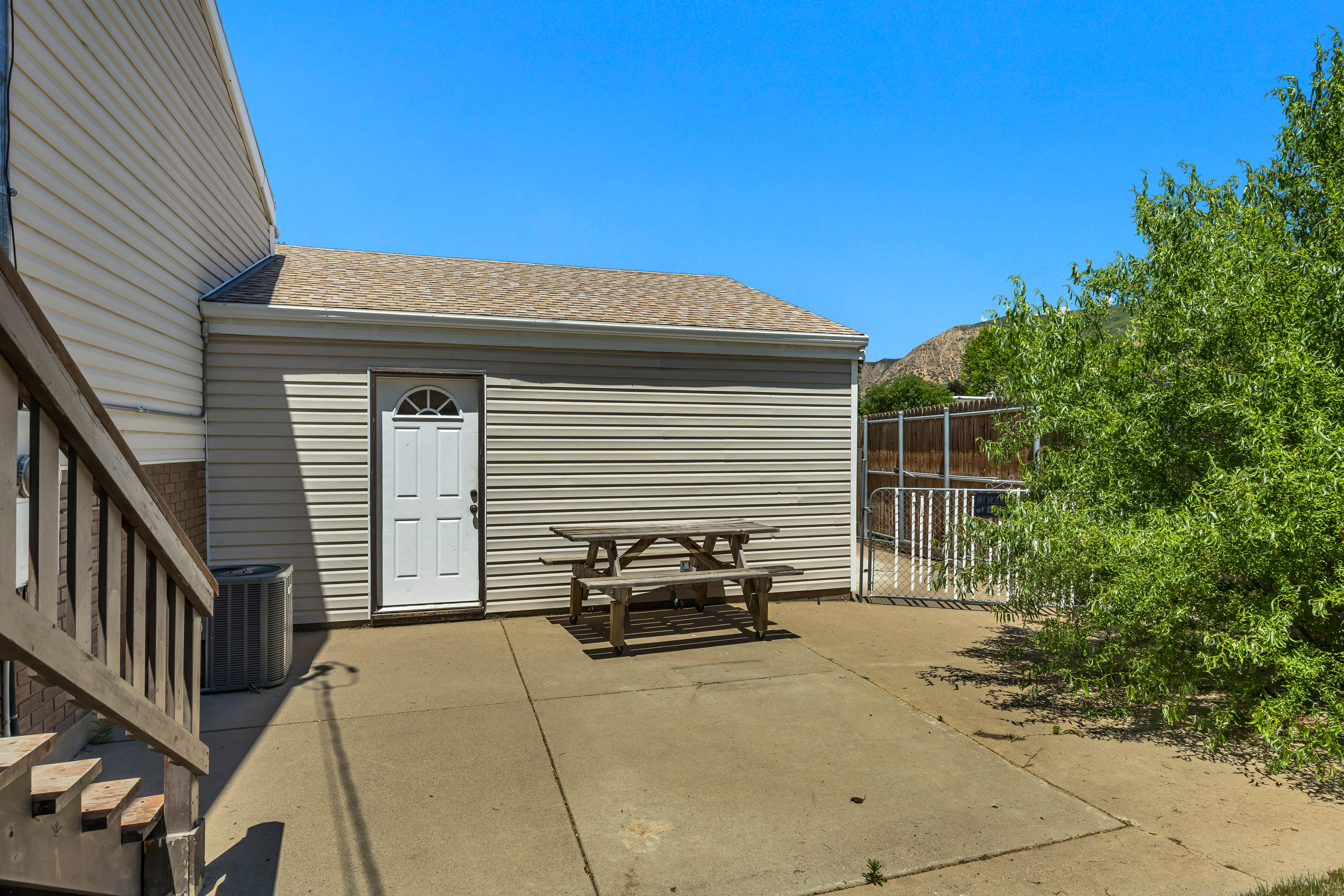 Attached outbuilding with side entry door, concrete patio area, and partial mountain scenery
