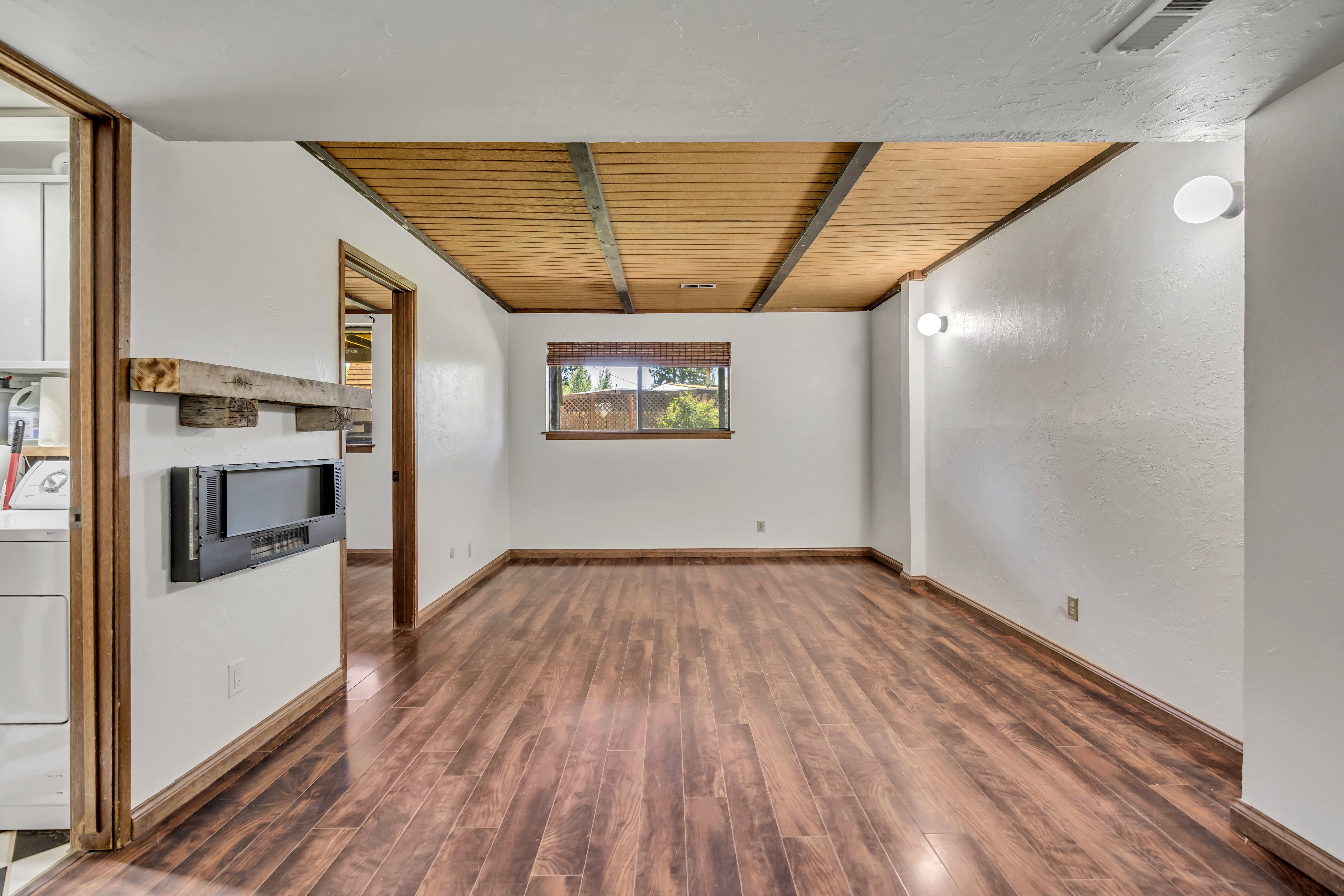 Spacious room featuring wood-finish flooring, a built-in fireplace, and a wood-paneled ceiling