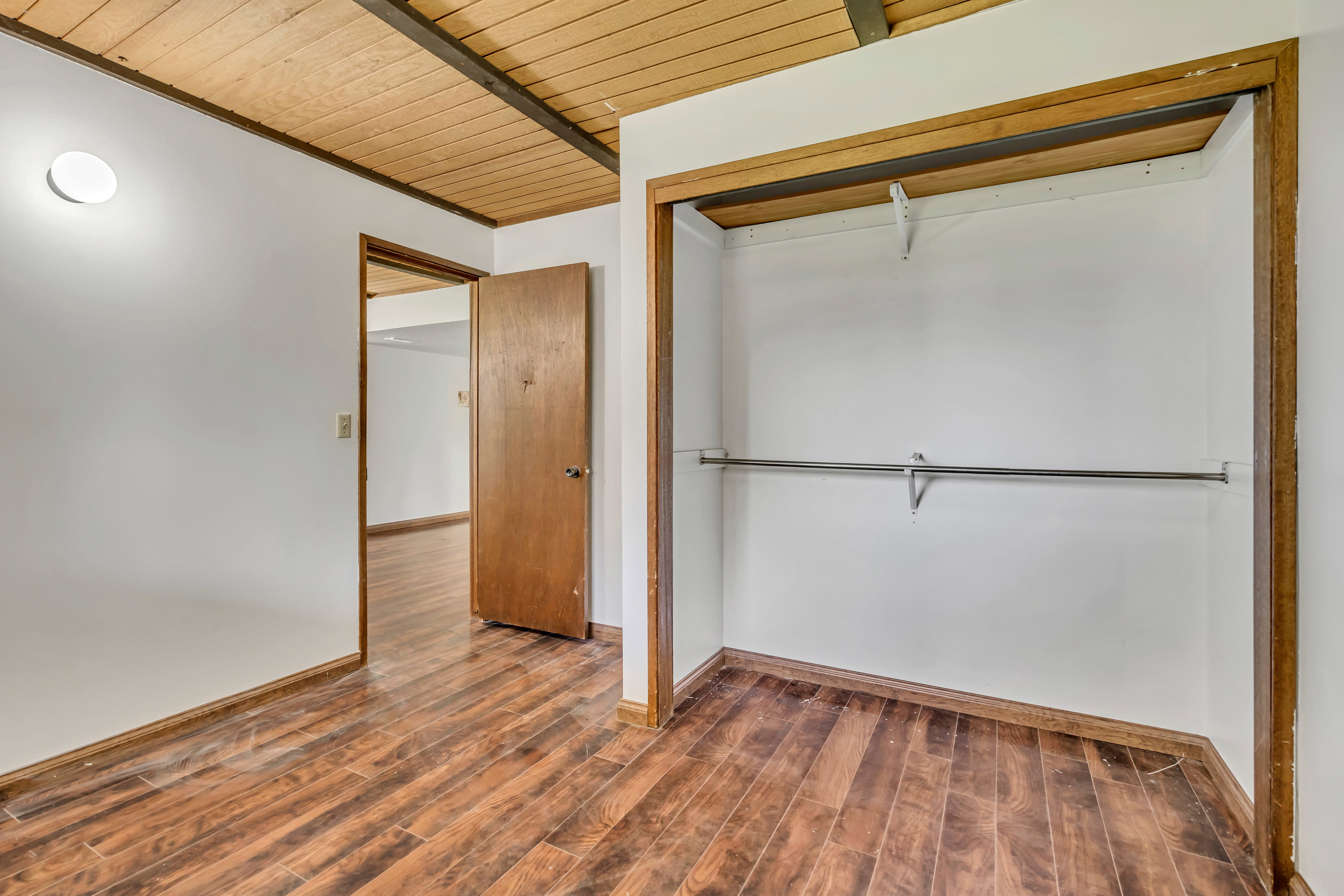 Room featuring wood-finish flooring, white walls, and a wood plank ceiling