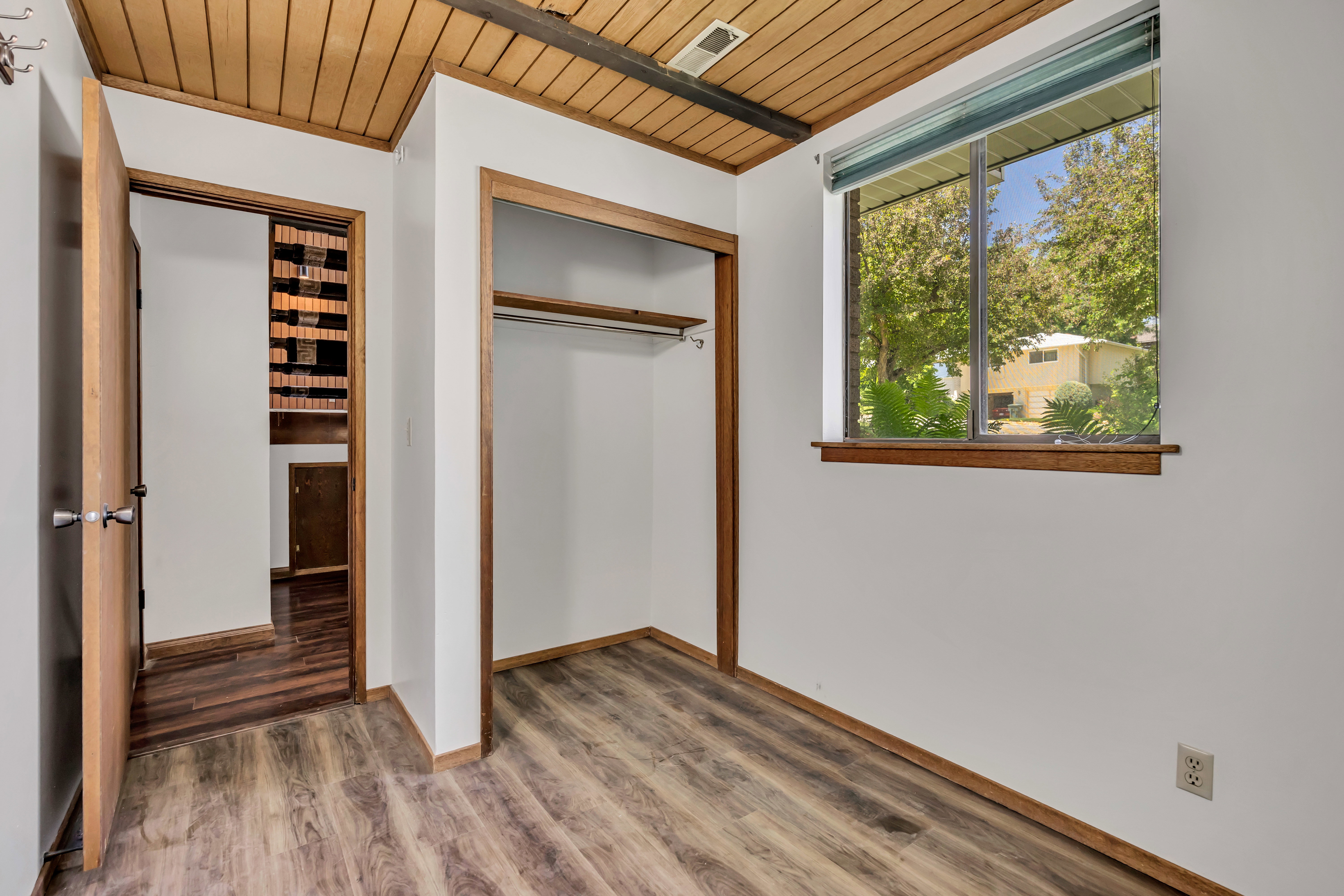 Room featuring wood-finish flooring, a wood-paneled ceiling, and a window with wood trim