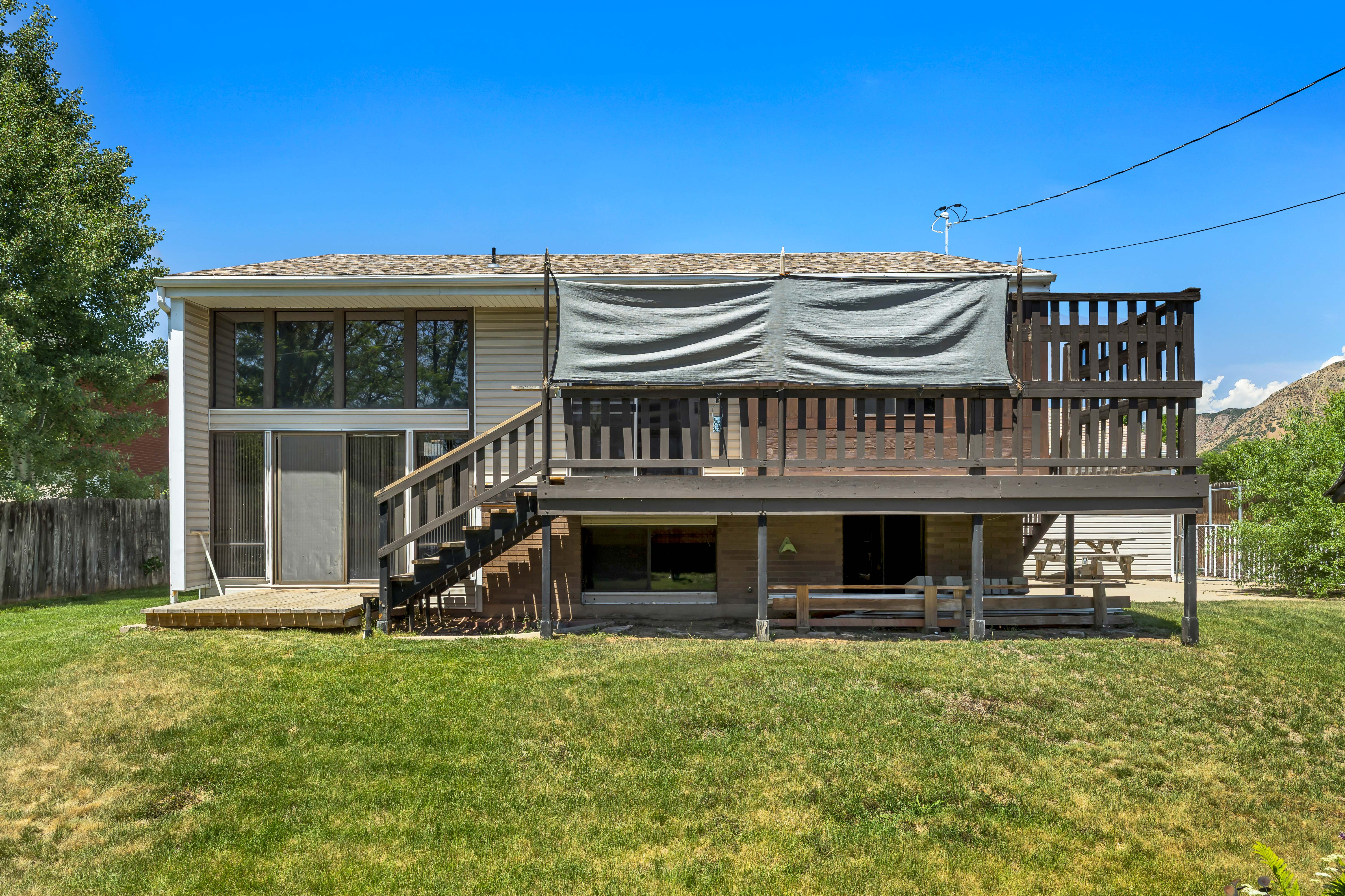 Expansive backyard featuring a multi-level deck, a lower-level patio, and a wall of windows and sliding glass doors