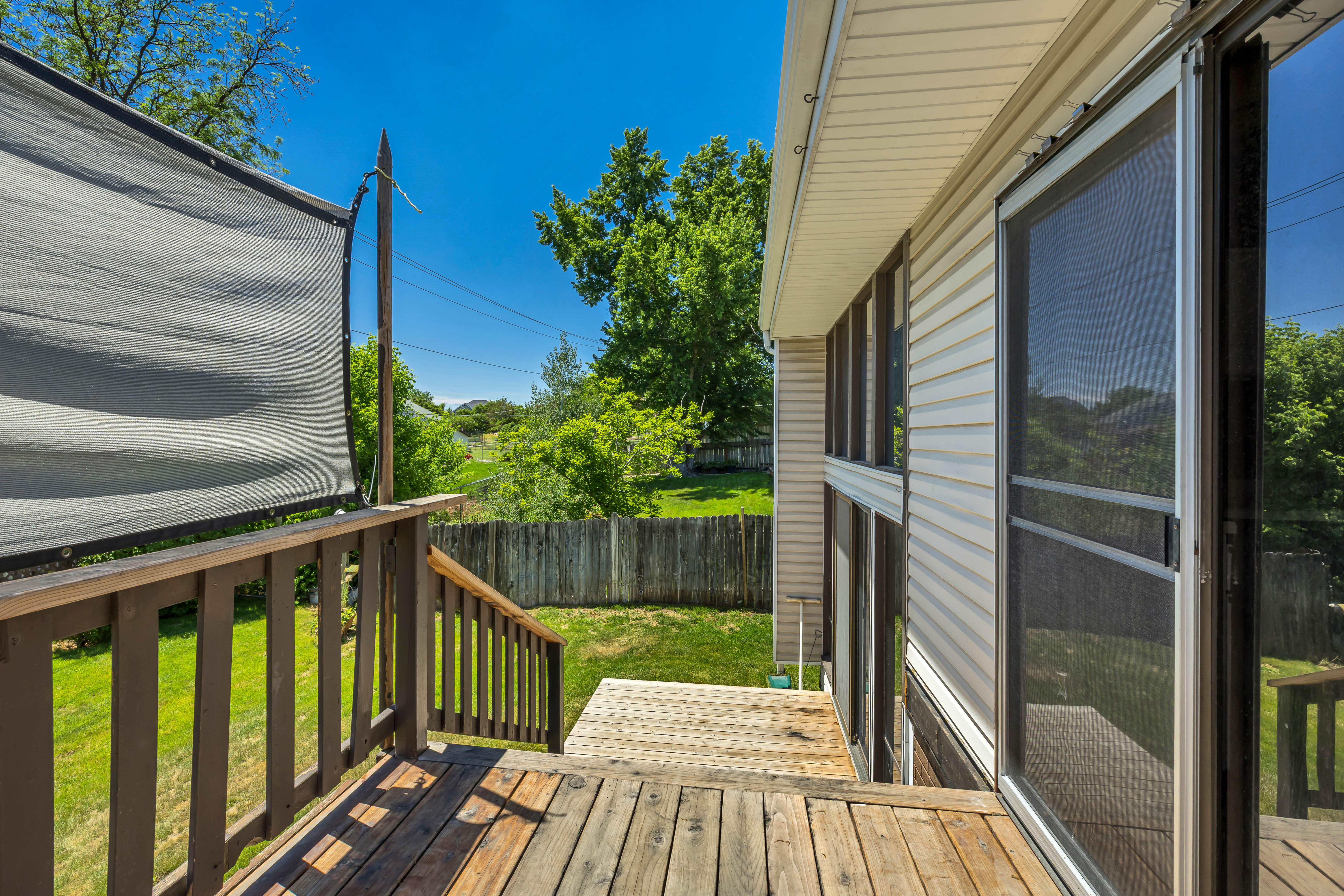Outdoor wooden deck with railings, offering direct access to the grassy yard