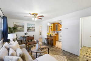 Open concept living area featuring wood-finish flooring, a ceiling fan with integrated lighting, and a dining space