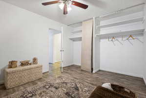 Room featuring wood-finish flooring, a ceiling fan, and white walls