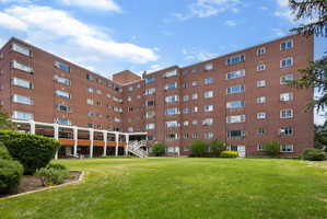 Brick multi-story building featuring multiple windows and a prominent courtyard