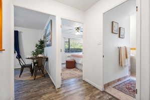 Hallway featuring wood-finish flooring, white walls, and bright overhead lighting