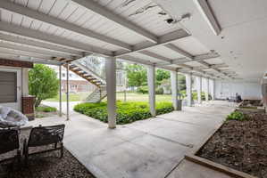 Spacious covered walkway featuring concrete flooring and exposed beam ceiling
