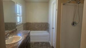 Bathroom vanity with an integrated sink, a rectangular mirror, and a window with blinds