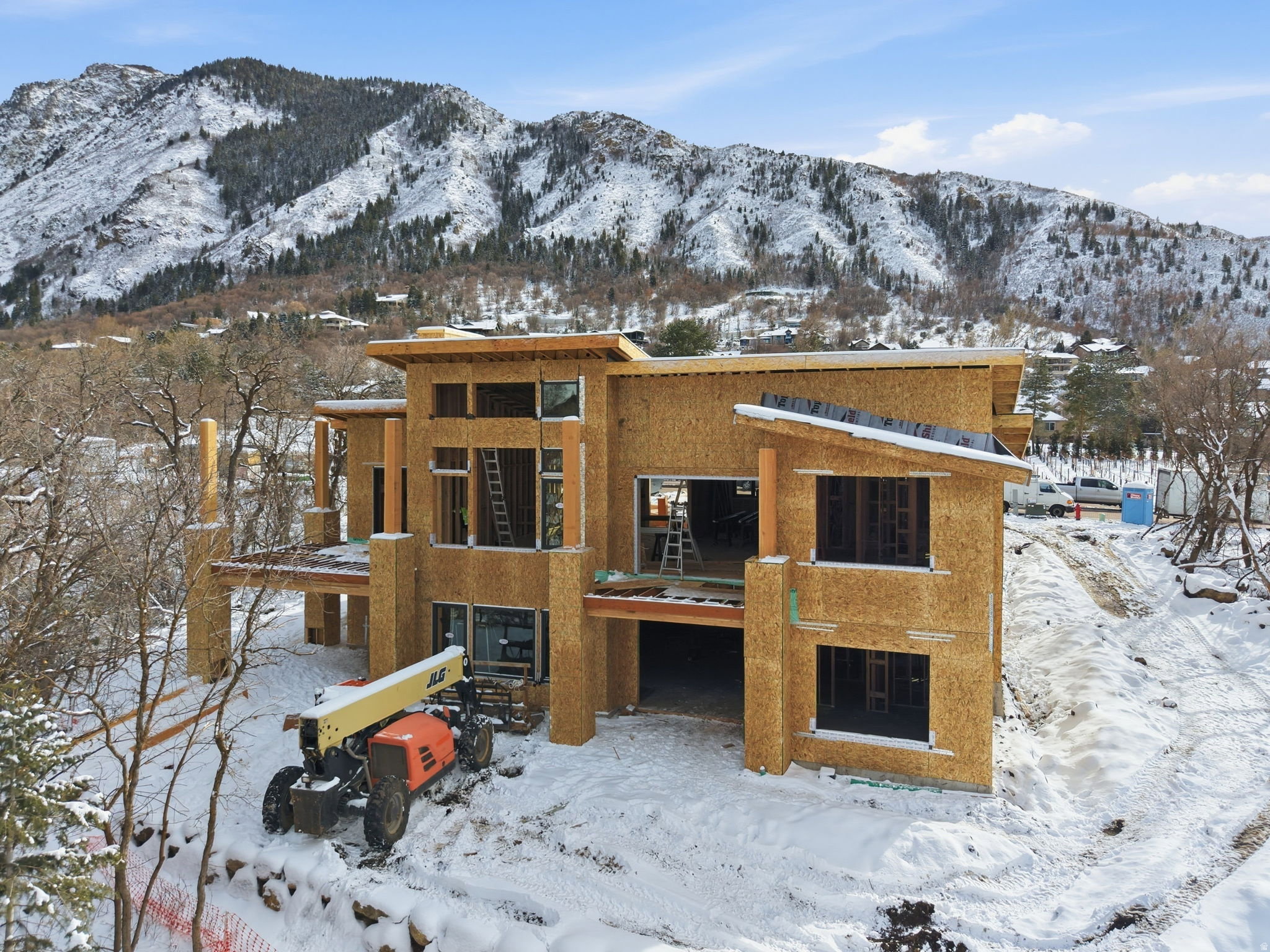 Contemporary-style home under construction with expansive windows, multiple outdoor patio spaces, and structural beams