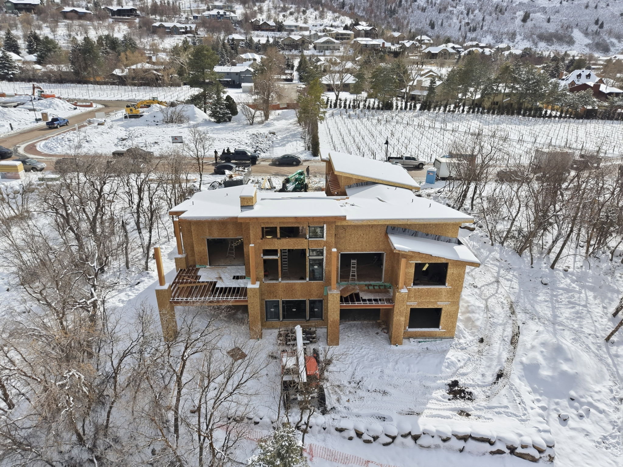 New construction framing with multiple large window openings, a multi-level deck structure, and a partially framed roofline