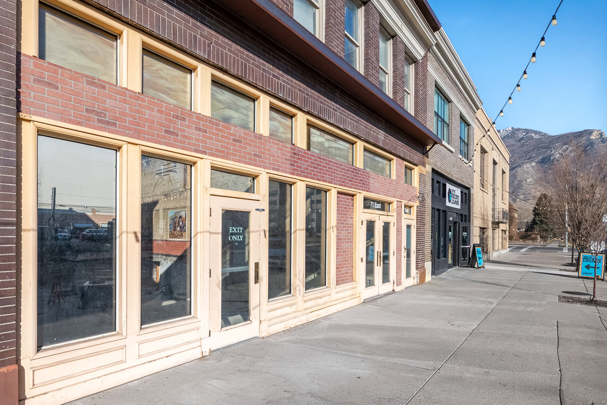 Brick facade building with large street-level storefront windows and transom windows