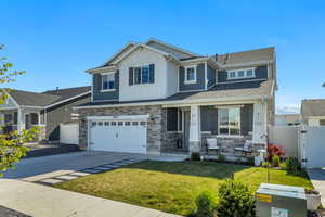 Two-story residence featuring stone veneer and horizontal siding with decorative shingles