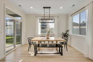 Bright room featuring light wood-finish flooring, white walls, and a contemporary linear chandelier