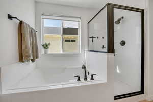 Built-in soaking tub with dark bronze fixtures, framed by a clear glass shower enclosure