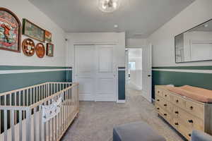 Carpeted room featuring a ceiling light fixture, white sliding closet doors, and two-tone wall paint