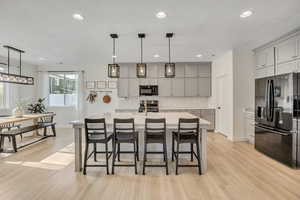 Open-concept kitchen featuring light wood-finish flooring, a central island with countertop seating, and recessed lighting