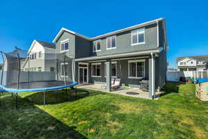 Expansive backyard featuring a manicured lawn, a covered patio, and a sliding glass door entry