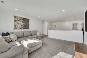 Expansive open-concept room featuring plush carpet flooring, recessed lighting, and crisp white walls