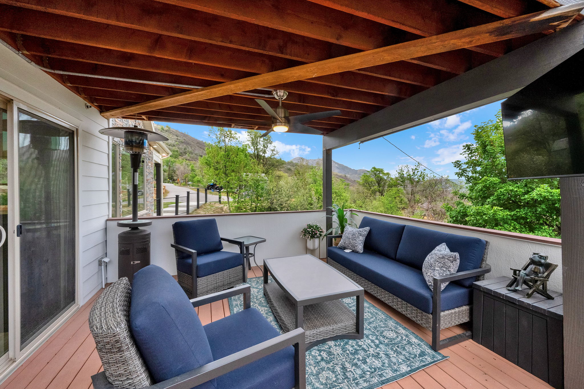 Covered outdoor patio featuring a wood-finish ceiling with exposed beams, a ceiling fan, and a mounted screen