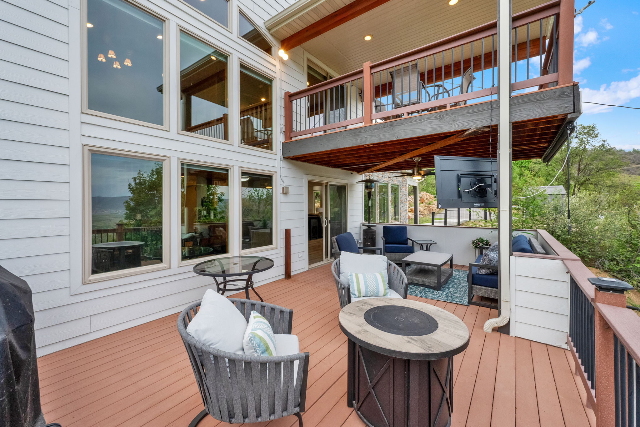 Multi-level outdoor living space featuring a spacious lower deck with a built-in outdoor media screen