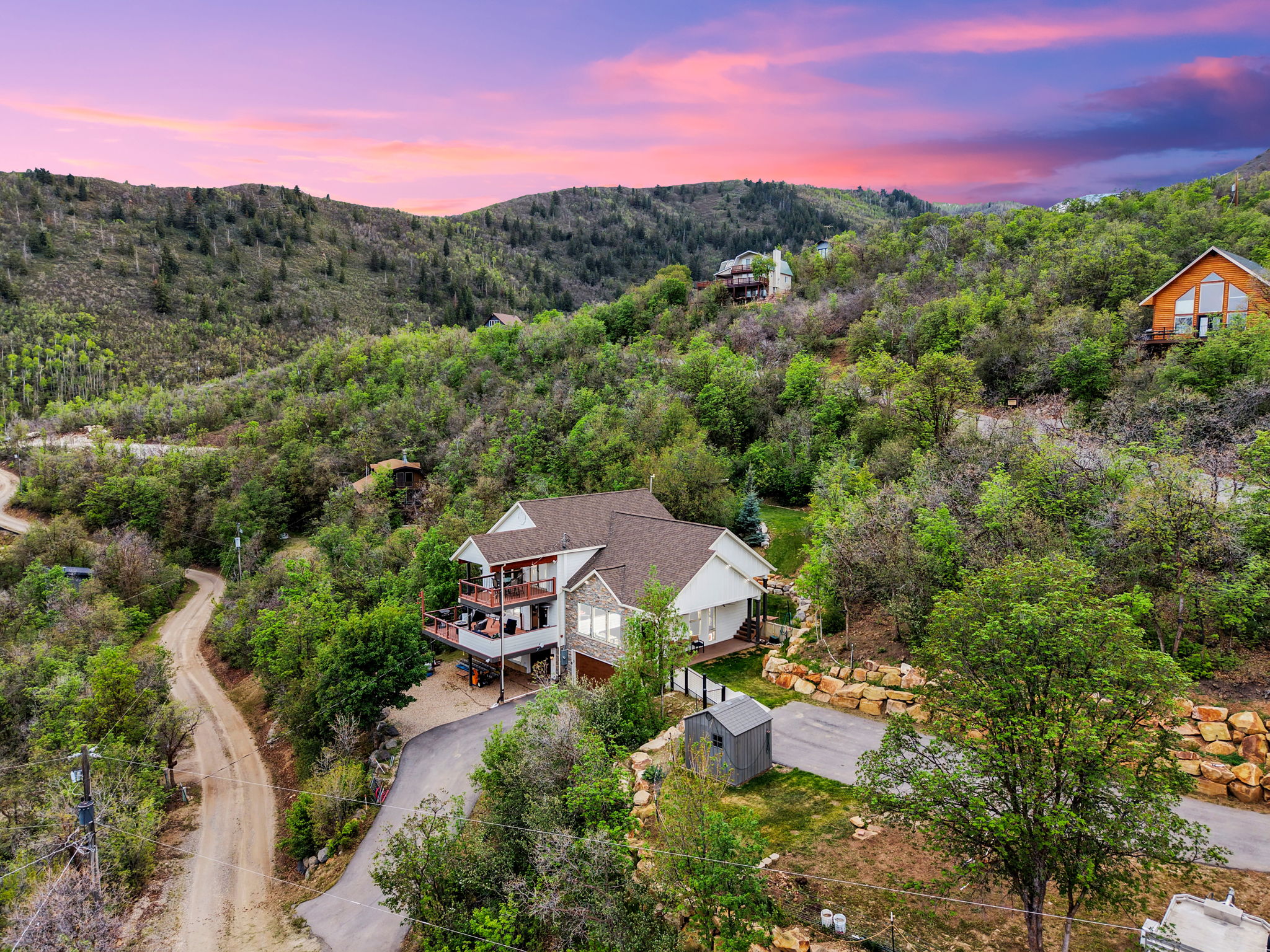 Hillside residence featuring multiple outdoor decks, a stone and siding exterior, and a prominent brown shingle roof