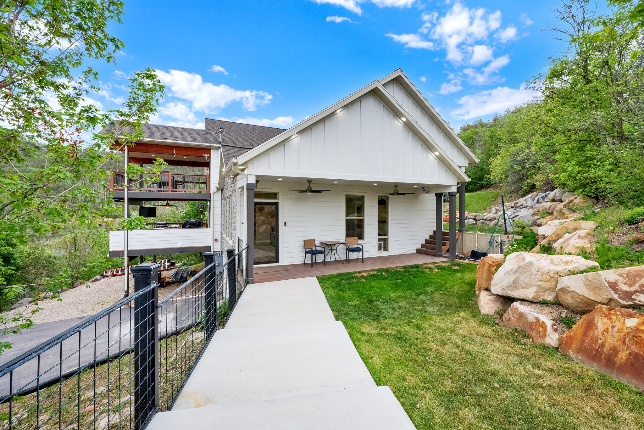 Contemporary-style residence with white board and batten siding, multiple levels of outdoor living spaces, and a gabled roofline