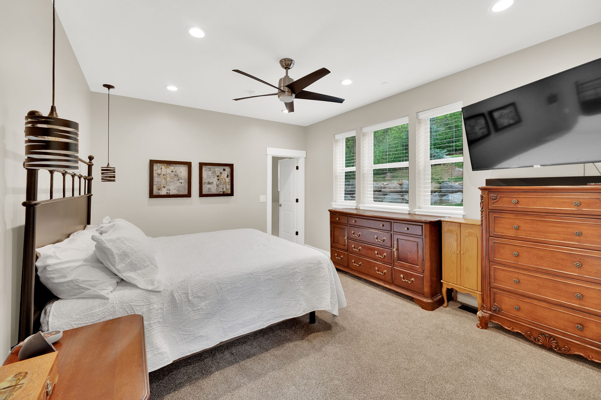 Carpeted room featuring a ceiling fan, recessed lighting, and three windows