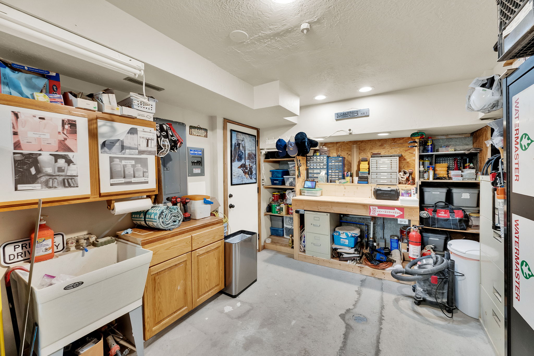 Utility space featuring a workbench with built-in shelving, a large utility sink, wood-finish cabinetry, and recessed lighting