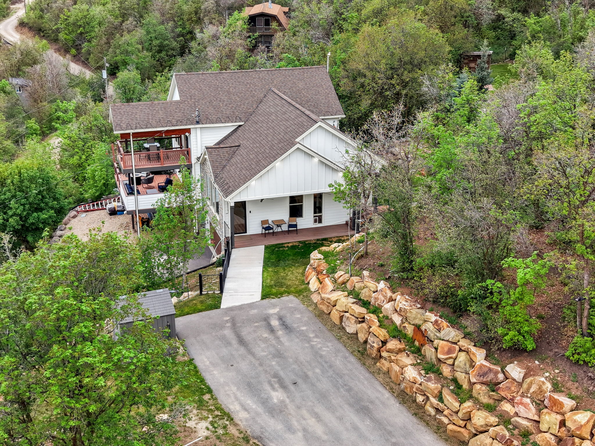 Multi-level residence featuring white vertical siding and brown shingle roofing