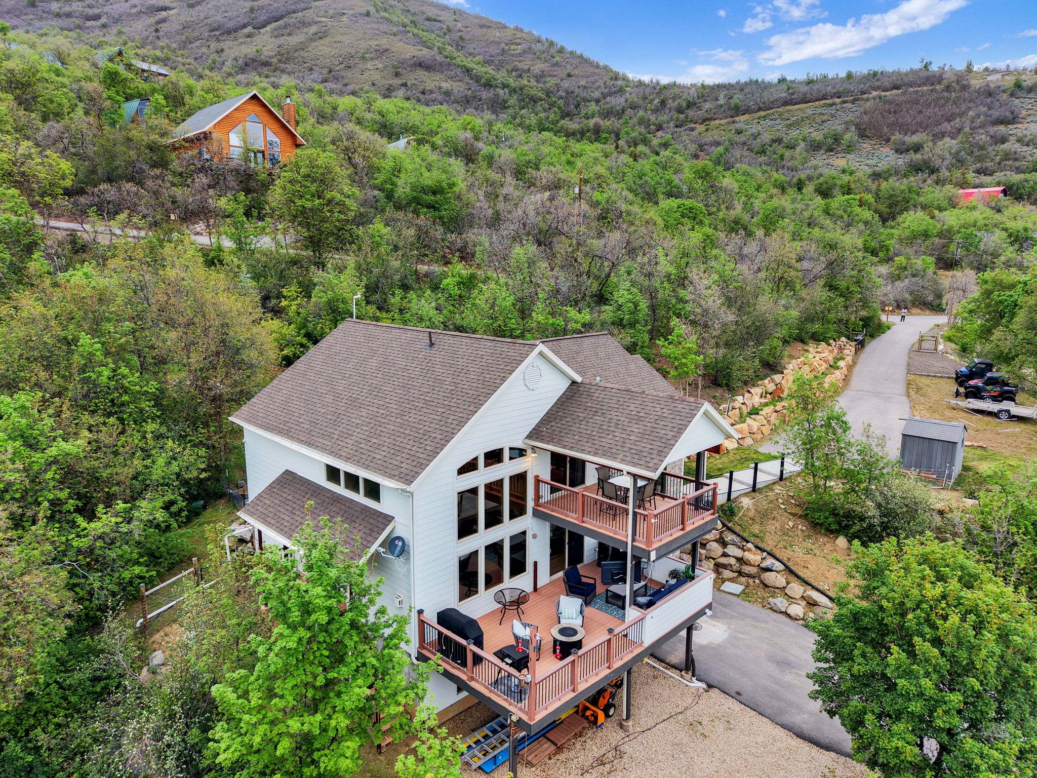 Contemporary residence featuring multiple expansive decks, a full wall of windows, and a detached storage shed