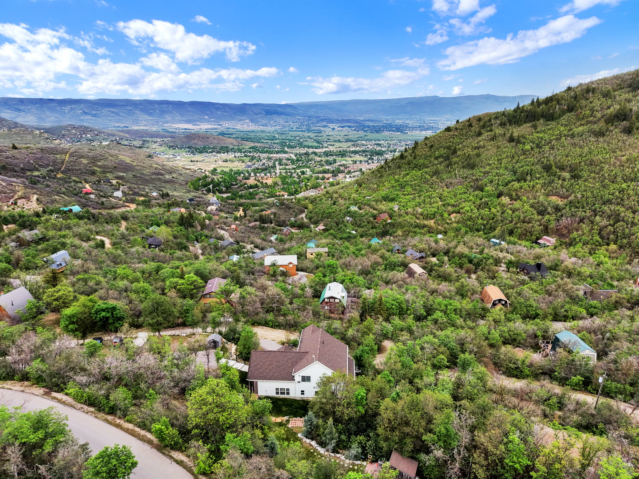 Expansive mountain landscape with scattered residences among abundant greenery
