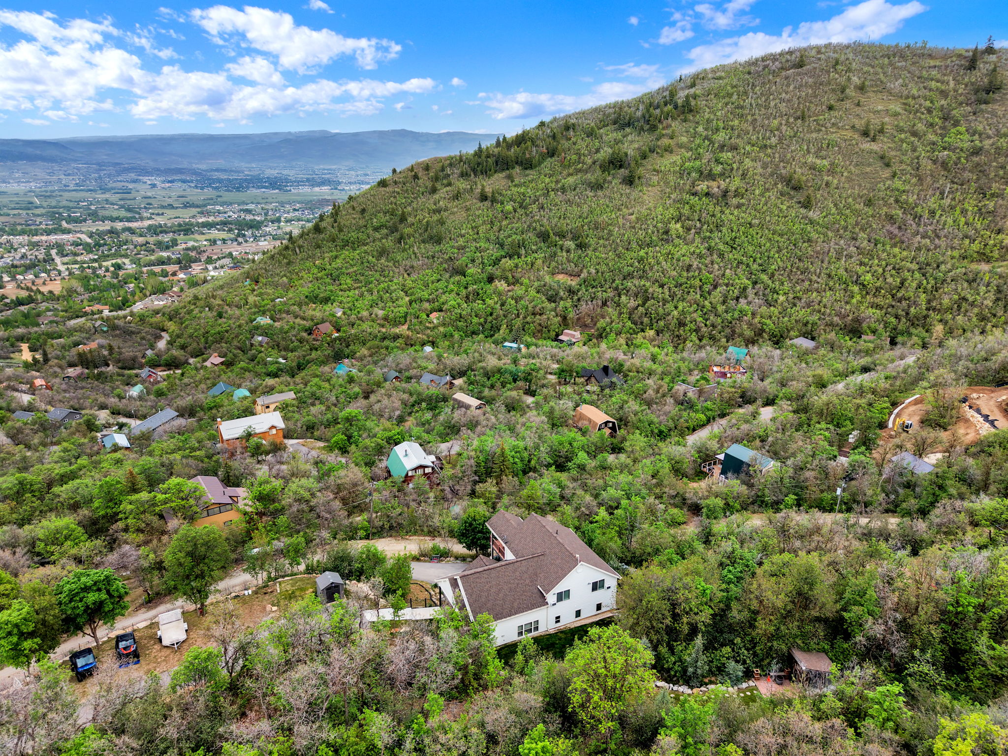 Expansive aerial perspective showcasing a hillside setting with numerous homes nestled among dense green foliage