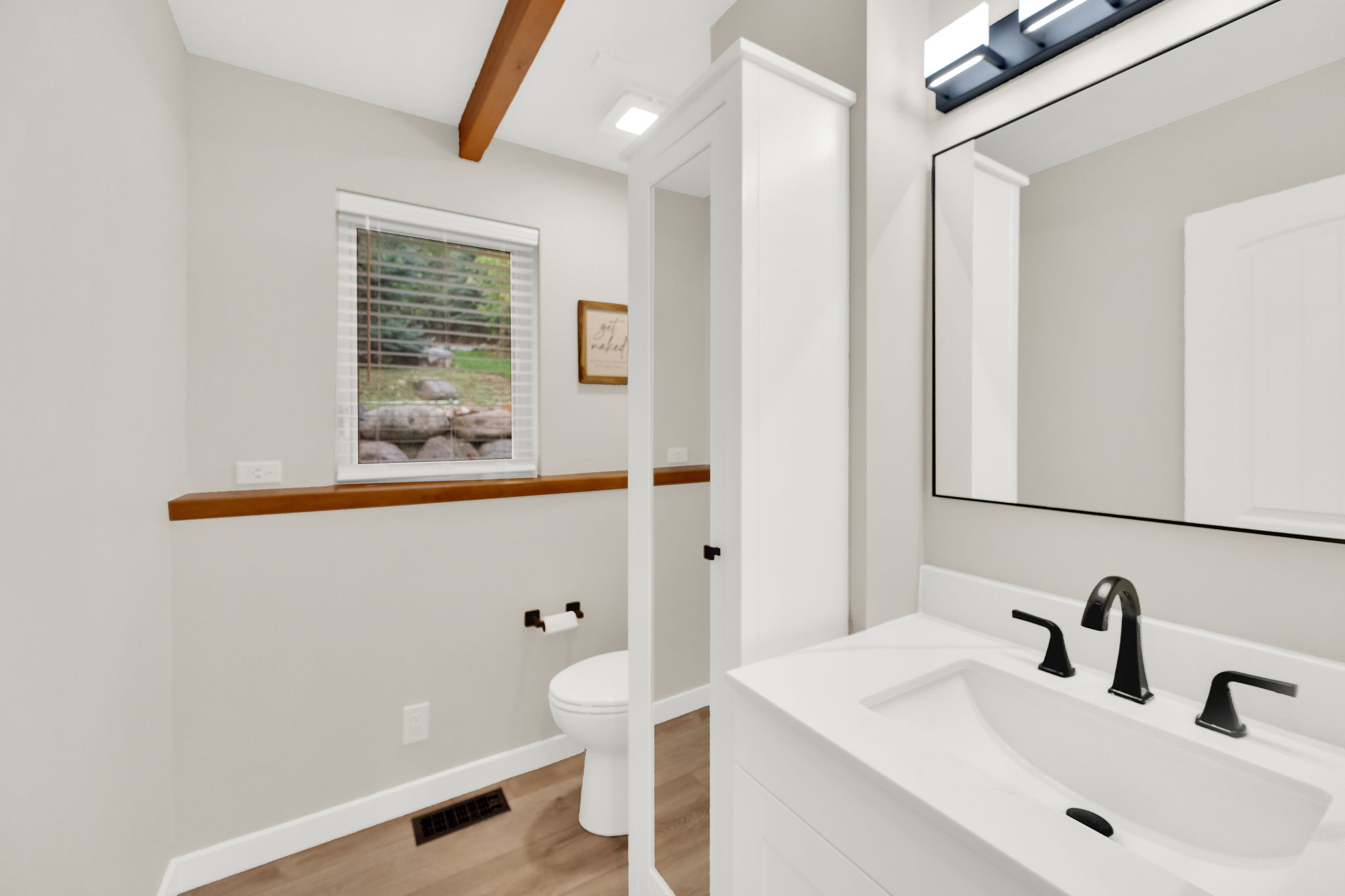 Bathroom featuring a white vanity with an integrated sink, matte black faucet, and a large framed mirror