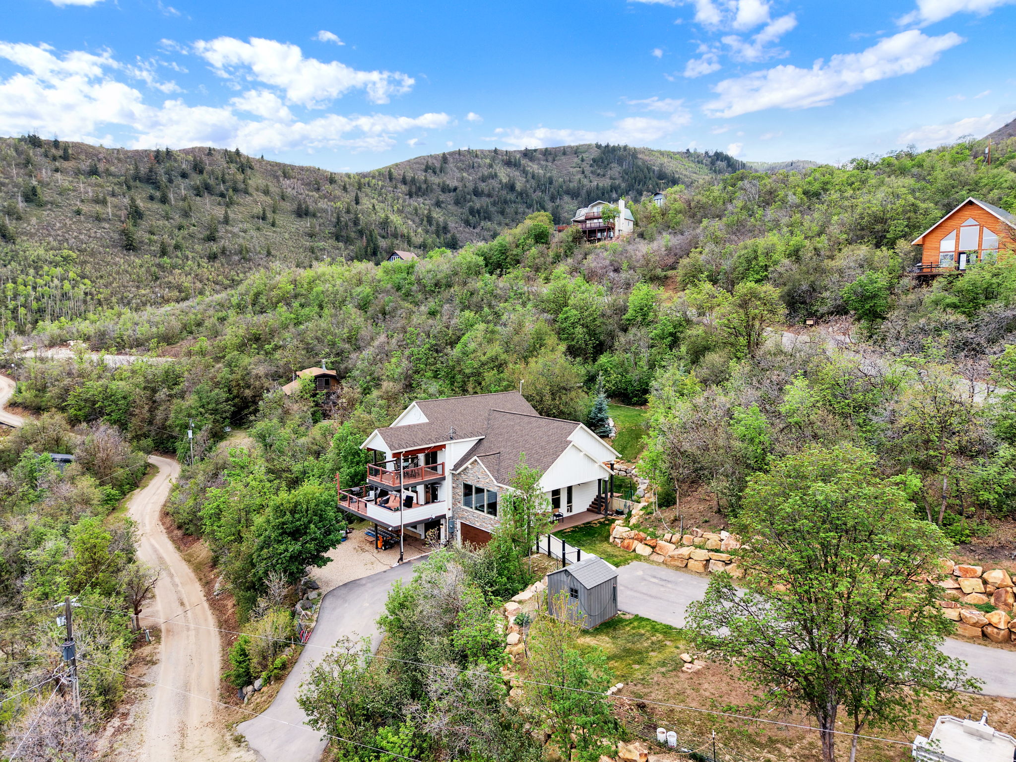 Hillside property with a tiered deck, stone façade accents, and a paved driveway