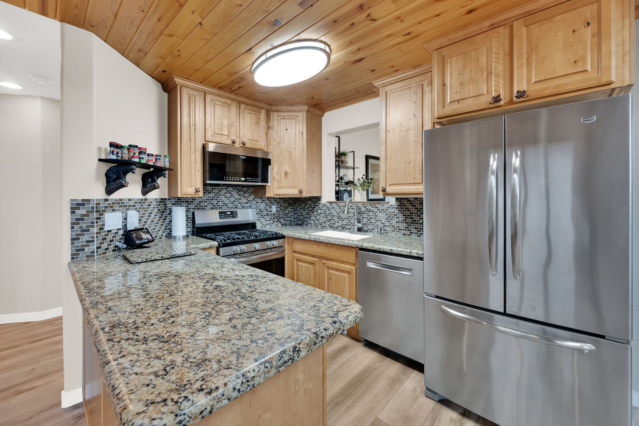 Kitchen featuring a wood-panel ceiling, light wood cabinetry, and a granite-finish countertop