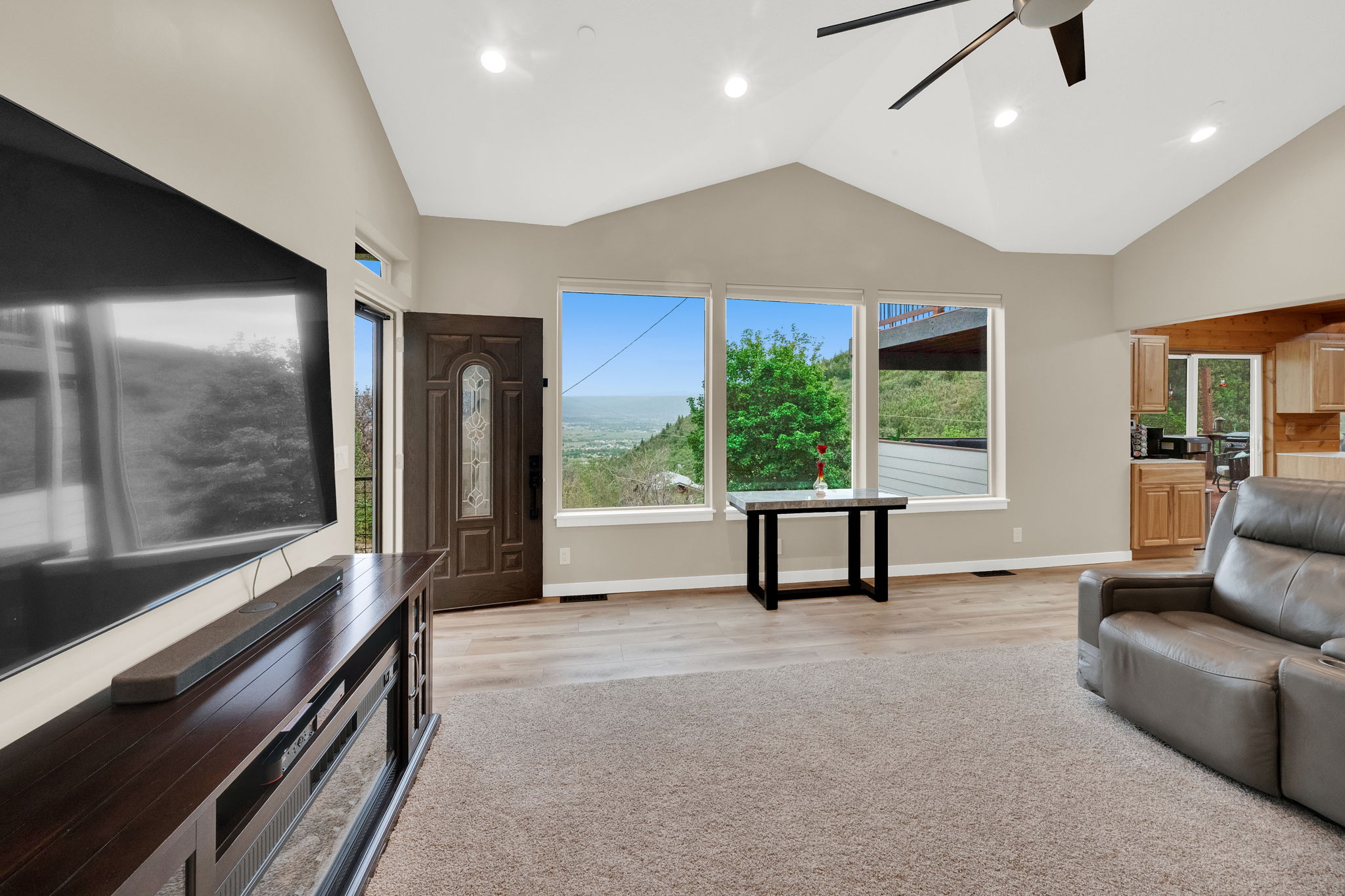 Spacious living area featuring a vaulted ceiling and panoramic windows overlooking a scenic landscape