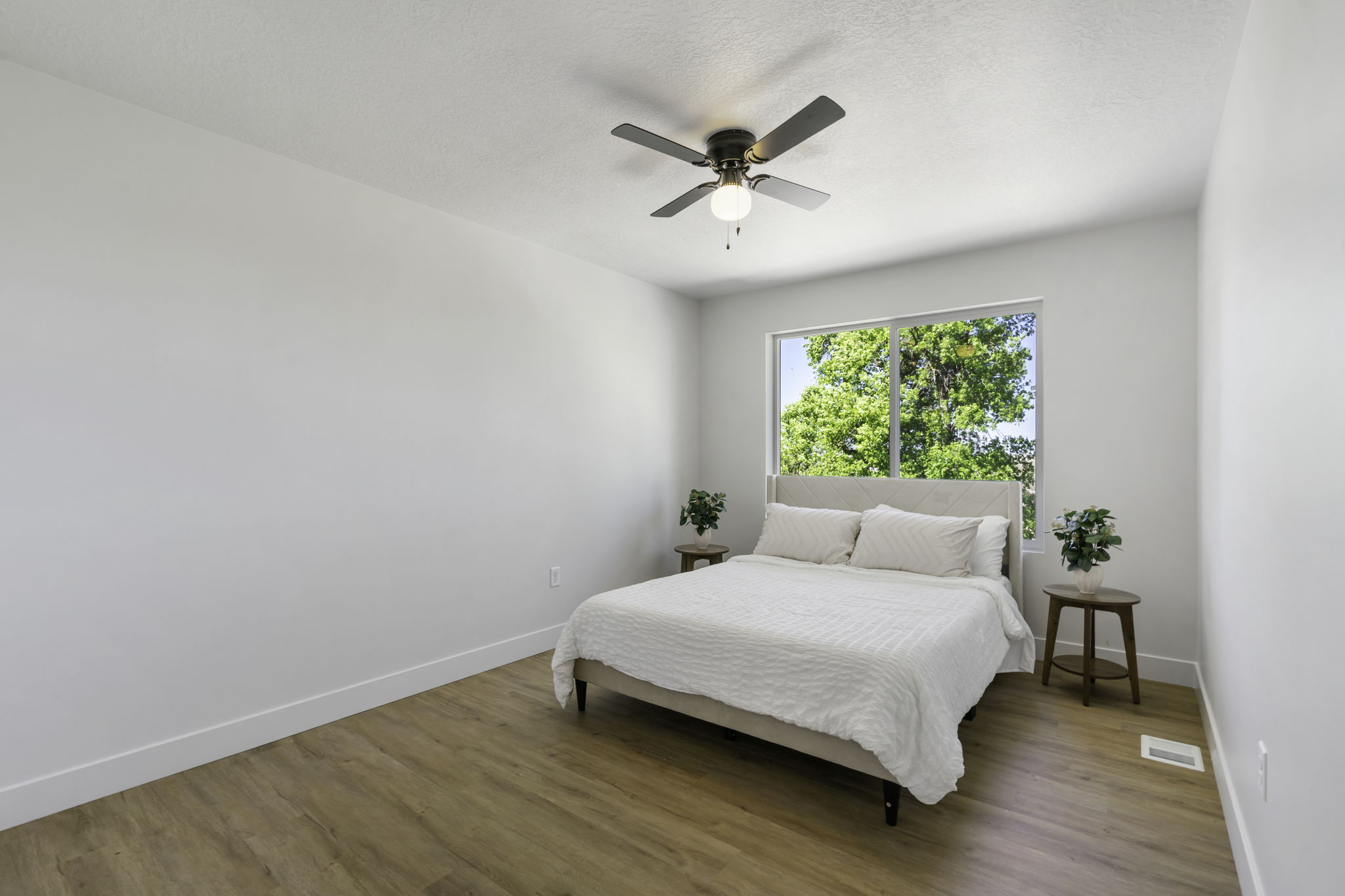 Bedroom featuring wood-finish flooring, white walls, and a large window