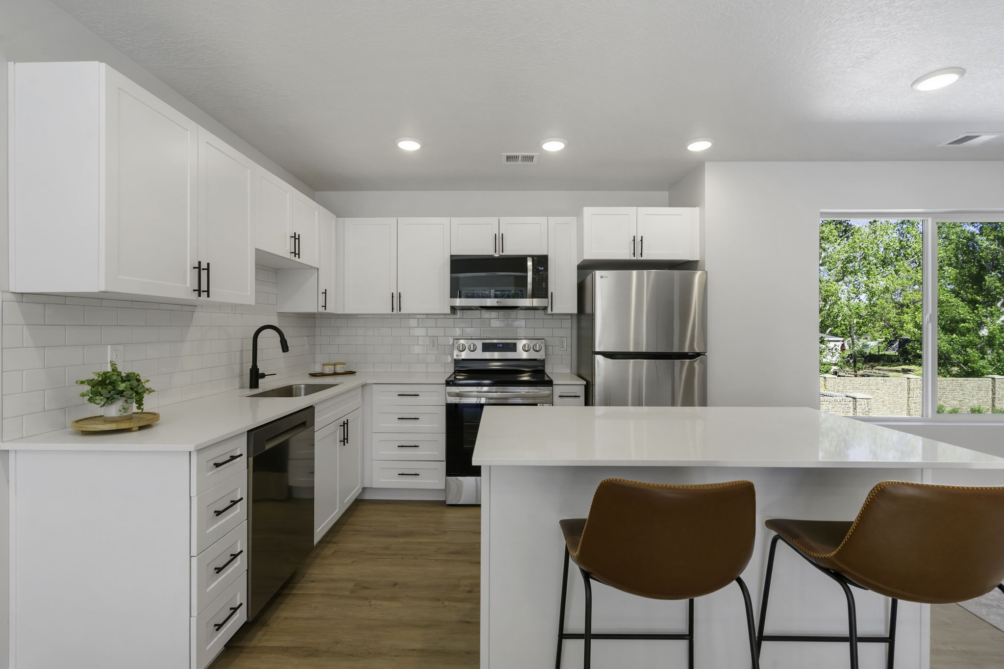 Contemporary kitchen featuring white cabinetry, stainless steel appliances, a white subway tile backsplash, and light-toned countertops